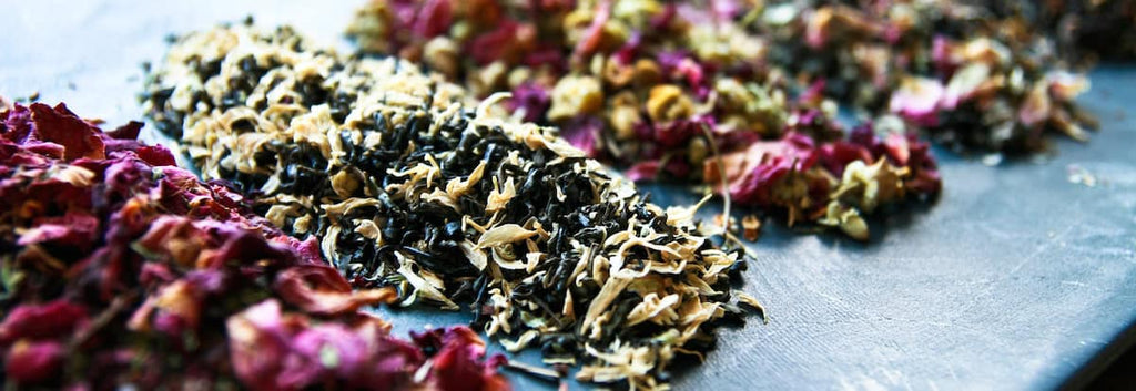Close-up of TOCHA Tea’s organic loose-leaf tea blends with floral and herbal ingredients on a dark stone background